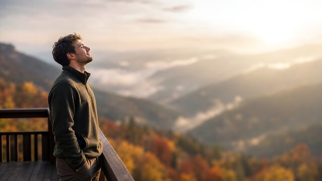 Profile view of an anonymous man breathing fresh air on a mountain deck at sunset, embodying deep relaxation, freedom, and triumph after a long autumn hike