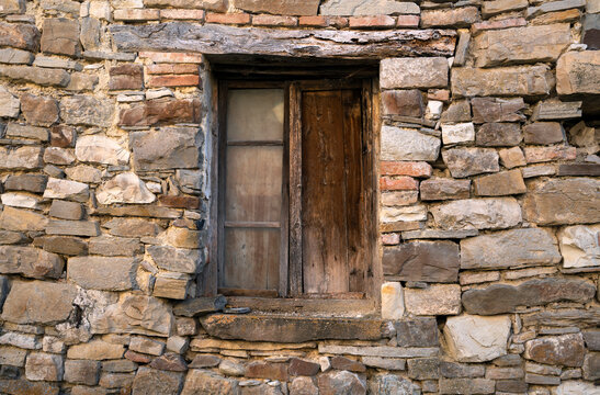 Old wooden window in stone wall in a rustic country house