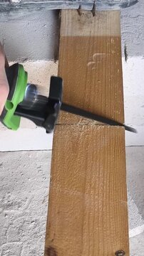 Electric reciprocating saw cutting a wooden beam with a wood blade. Close-up of a power tool in action during woodworking and construction.