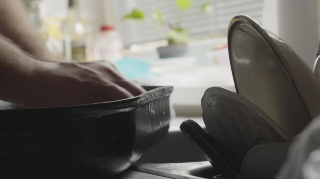 Close-up of detergent being applied and scrubbed into stubborn cookware stains. Highlights household cleaning, hygiene, effort, maintenance, and domestic chores.