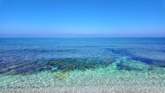 Stunning turquoise crystal clear water at Is Arutas beach in Sardinia, Italy. Transparent sea with rocky seabed under a clean blue sky and wide ocean horizon