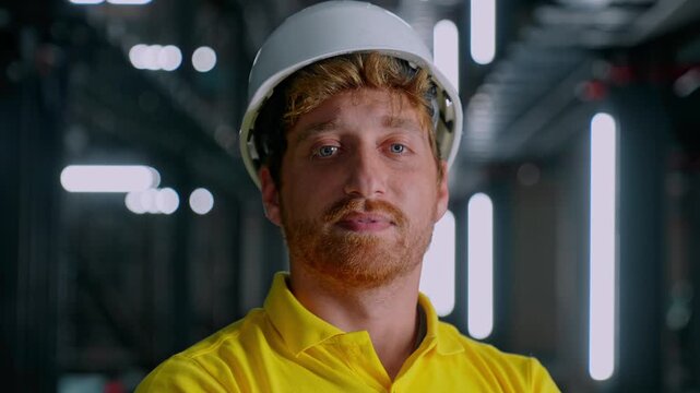 Helmeted engineer standing inside a modern technical facility, showing professional confidence, workplace safety, system supervision and industrial operations in an automated parking environment.