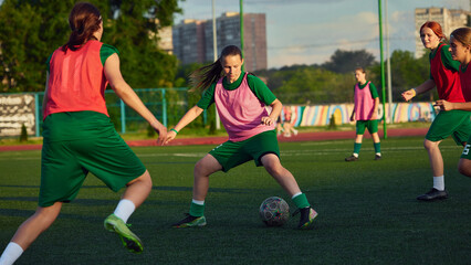 Teenage female soccer player dribbling ball during team football practice. Concept of ball control,...