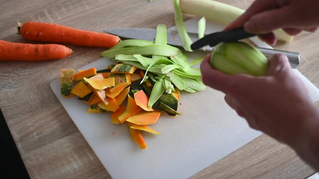 Peeling Fresh Zucchini with Vegetable Peeler in Kitchen
