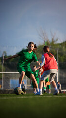 Obraz premium Female teen soccer player dribbling ball against defender on field. Concept of women football, competitive play, resilience, youth academy and match action.