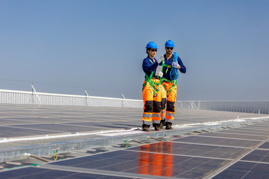 Engineers inspecting solar panel installation on a commercial rooftop, Professional technicians team maintaining solar energy infrastructure site on a sunny day