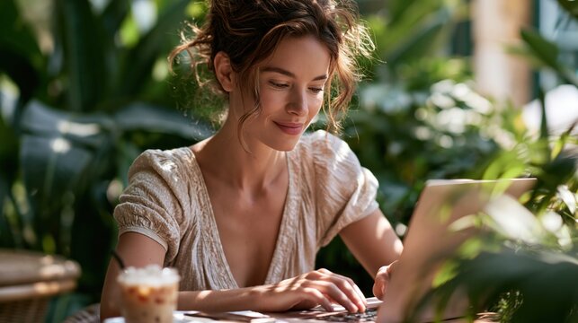 Young woman focused on her laptop while surrounded by vibrant indoor plants in a warm and inviting cafe atmosphere