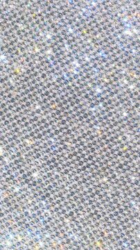Rotating Sparkling Rhinestone. Macro video of faceted crystals sparkling intensely with smooth rotational camera movement on white surface.