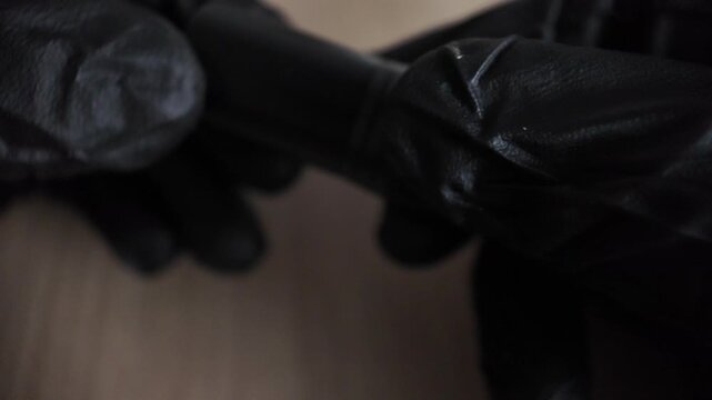 Detailed macro close up of hands in black gloves inspecting a professional 3-pin XLR male plug to mini jack connector audio adapter.