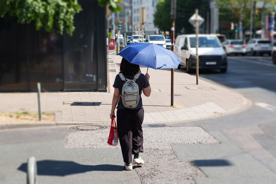 Person using an umbrella for shade while walking during an extreme summer heat wave in Dusseldorf, Germany