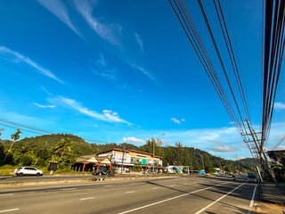 Obraz premium A beautiful wide-angle horizontal photograph showcasing an empty multi-lane highway running along a scenic tropical landscape in Southeast Asia