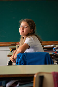 Smiling elementary school girl looking back at classmates