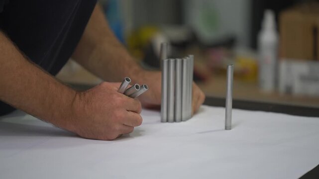 Worker assembling aluminum strip components at sign workshop bench closeup