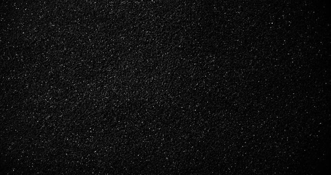 Black speckled texture slow rotation. Close-up of dense fine white particles on deep black surface. Smooth continuous rotation reveals subtle sparkling shifts and light reflections.