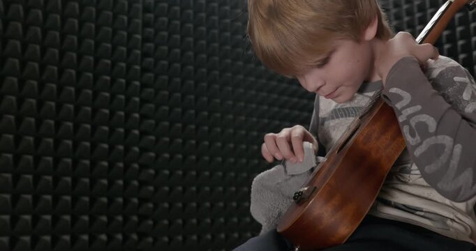 Boy Wipes Dust Cleaning Ukulele Instrument in Home Studio. 4K 10-bit