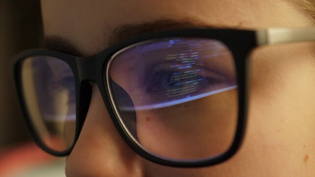 Software Developer, Artificial Intelligence and Programming. Coding Encryptions Scroll Past Screen in Reflection of Software Engineers Eyeglasses. Young Woman Behind Computer Coding in Dark Room.