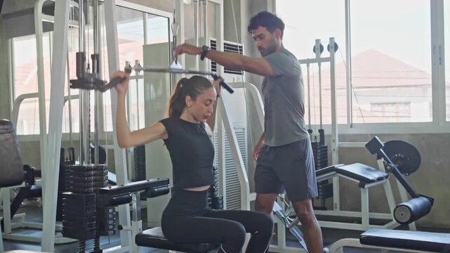 Fitness coach helping a client with strength exercises in a contemporary gym setting