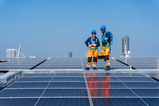 Team of Engineers inspecting solar panel installation on a commercial rooftop, Technicians team in safety gear surveying solar panels at a power plant site