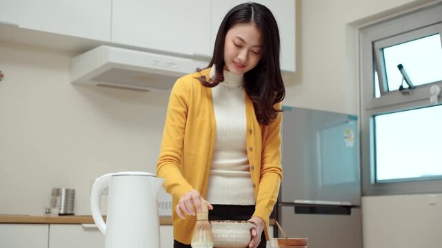 Pretty young woman making traditional green tea matcha using bamboo natural whisk mixing beverage for healthy drink with antioxidant nutrition in wellness routine and modern healthy lifestyle.
