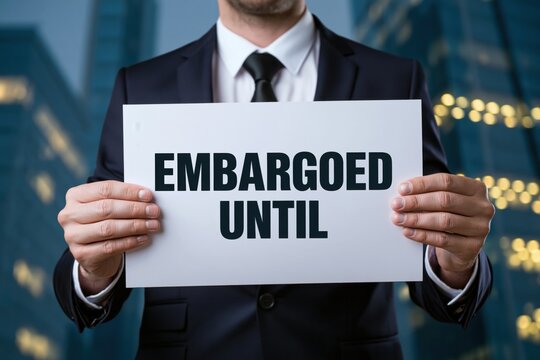 Corporate businessman holding a white paper document with the text embargoed until