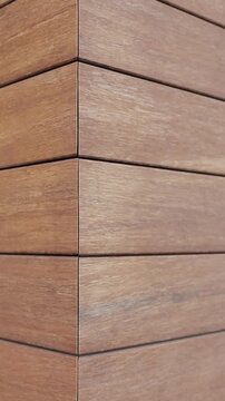Vertical video. Close-up of exterior wall with wood-look cladding on modern house.