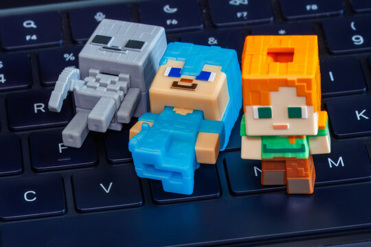 Plastic Minecraft character figures laying on a computer keyboard. Minecraft is a popular sandbox video game developed by Mojang Studios and acquired by Microsoft in 2014.
