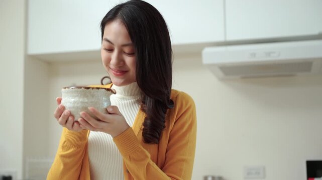 Happy woman enjoying the aroma of green matcha tea in a traditional Japanese cup. smiling female living peaceful relaxation with mindful wellness ritual and self-care moment healthy lifestyle.
