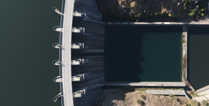 Aerial view of Barragem do Torrao showing the concrete dam structure, deep water reservoir, and surrounding rocky terrain in Alpendurada e Matos, Porto, Portugal.