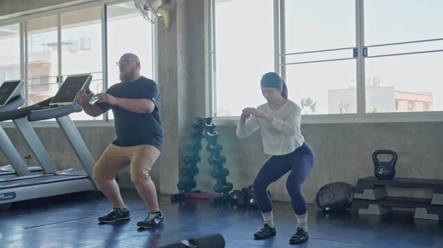 Fitness coach assisting individual with exercise regimen in contemporary gym environment