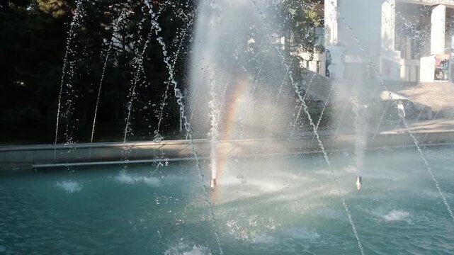 Multiple high-pressure nozzles shooting powerful streams of fresh water into the air at a public city park fountain. Summer heat, urban architecture, municipal engineering, public parks in summer.