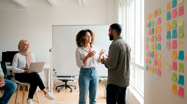 Inclusive diverse team in animated discussion with colorful sticky notes on office wall