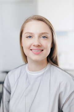 Portrait Smiling caucasian young female in white shirt in bright room in dental clinic