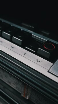 A male finger presses the mechanical play button of a vintage cassette recorder. Tight macro focus highlights the silver metal panel and retro audio symbols. Moody lighting adds a nostalgic vibe.