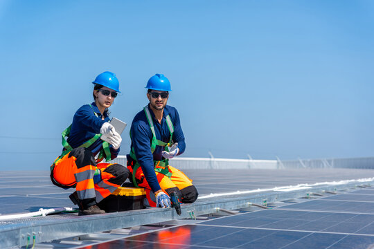Engineers installing and inspecting solar panels on a commercial rooftop, Professional technicians team in safety gear surveying solar photovoltaic panels at a site
