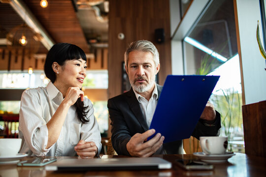 Two business colleagues reviewing documents at a cafe
