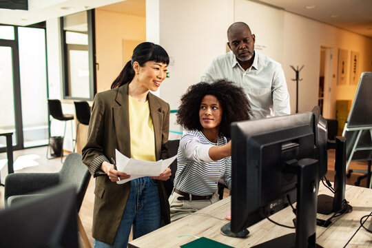 Three coworkers collaborating at a computer in a modern office