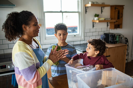 Parent and children sorting recycling in kitchen