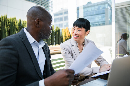 Business colleagues discussing documents at outdoor office