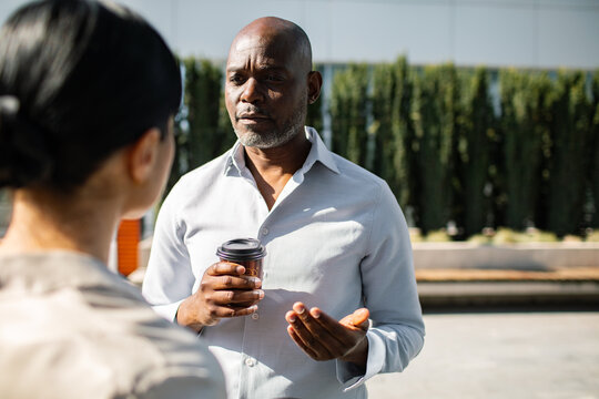 Mature businessman talking with colleague during outdoor coffee break