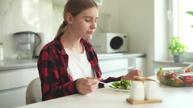 Teen Girl Eating Veggie Salad At Home In The Kitchen