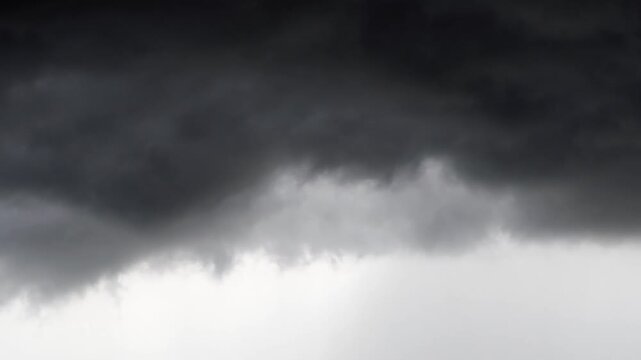 Ominous, swirling black clouds against a gray sky&mdash;a dramatic darkness associated with rain or a storm.