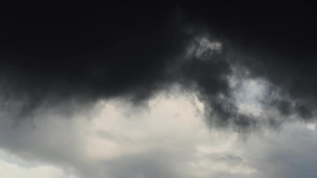 Ominous, swirling black clouds against a gray sky&mdash;a dramatic darkness associated with rain or a storm.