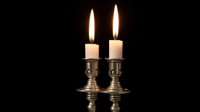 Two silver candlesticks with lit candles on dark background.