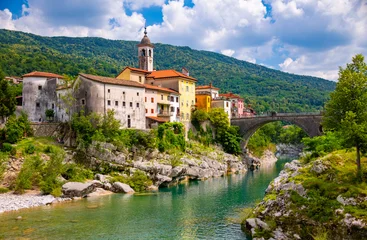 Kanal ob Soči is a charming village on the emerald-green Soča River in Slovenia. An idyllic summer panorama featuring a church, a bridge, and the crystal-clear waters of the river. © ON-Photography