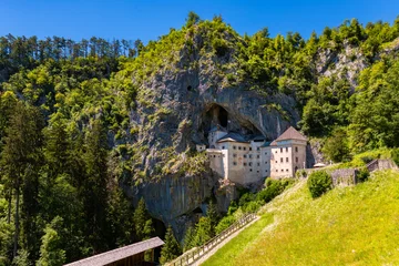Panorama of Predjama castle built in a cave in Slovenia. Popular tourist attraction and historic monument in an idyllic valley near Postojna Caves on a summer day. Wide angle scenery and major sight. © ON-Photography