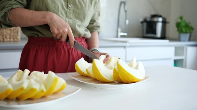 Woman Cutting Melon Into Pieces In The Kitchen Close-Up