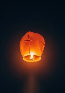Floating glowing paper lantern released at night, ascending high into the dark atmospheric heavens during a spiritual ceremony, glow, night, tradition