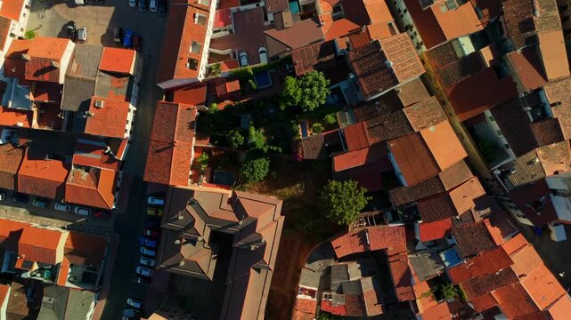 Low altitude drone captures an angled overhead view of dense terracotta rooftops and narrow lanes in the historic city of Caceres, Spain.
