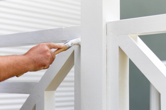 Peinture d'un garde-corps en bois blanc au pinceau, r&eacute;novation et entretien d'une terrasse ext&eacute;rieure