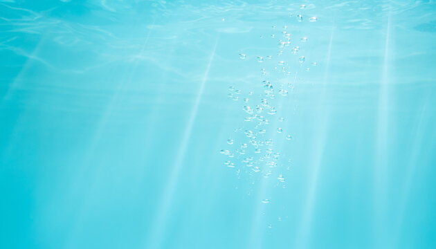 Rising air bubbles underwater with divine light rays in cyan sea ターコイズブルーの海中にまっすぐ差し込む神秘的な光の筋と気泡の背景